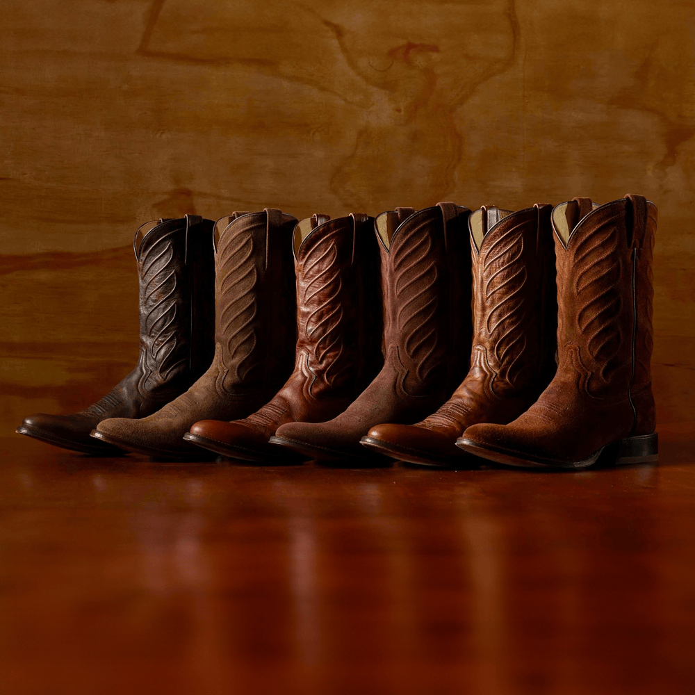 A lineup of Derby western boots in various colors on a wood surface. Shop the Derby Collection.